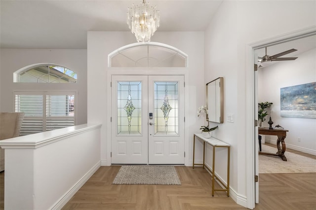 foyer featuring french doors, baseboards, and ceiling fan with notable chandelier