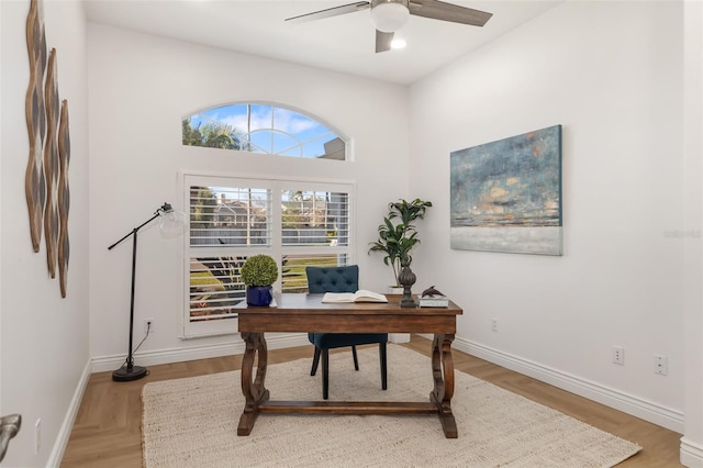 office area featuring light wood finished floors, baseboards, and a ceiling fan