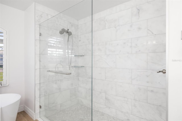 bathroom featuring a stall shower, a freestanding bath, and baseboards