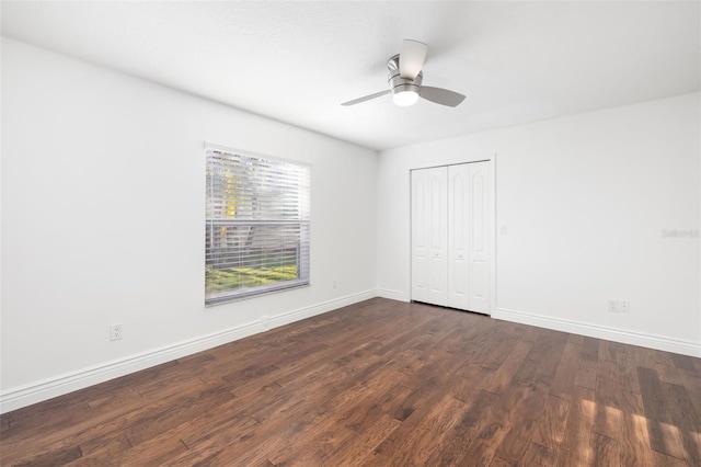 unfurnished bedroom featuring a ceiling fan, baseboards, dark wood finished floors, and a closet