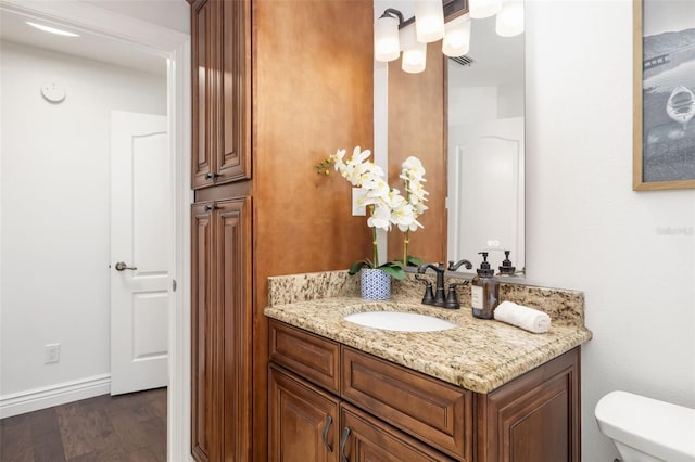 bathroom featuring toilet, wood finished floors, visible vents, vanity, and baseboards