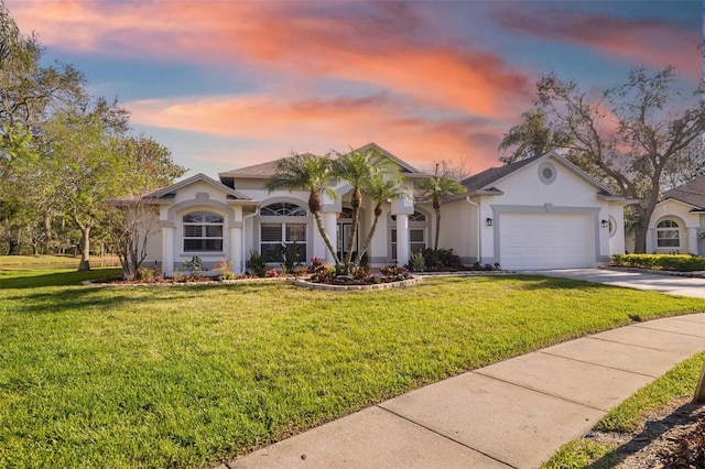 view of front of property with a front yard, concrete driveway, an attached garage, and stucco siding