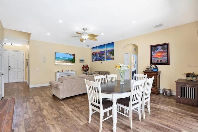 dining space with baseboards, visible vents, arched walkways, and wood finished floors