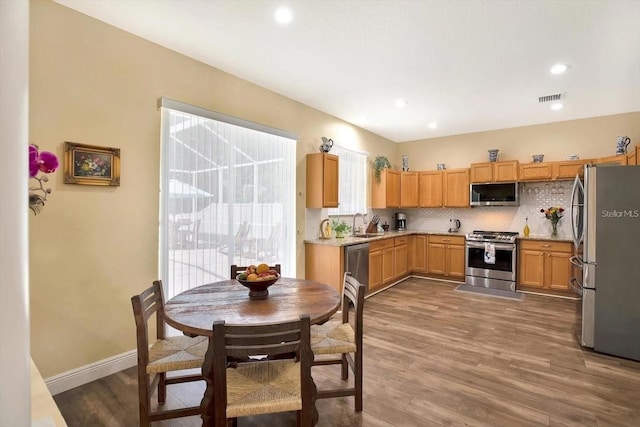 kitchen with baseboards, visible vents, decorative backsplash, appliances with stainless steel finishes, and wood finished floors