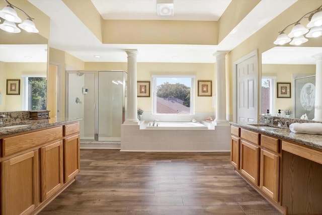 bathroom with a garden tub, decorative columns, a shower stall, and wood finished floors