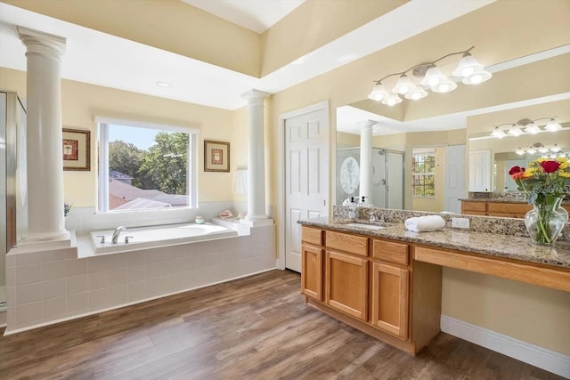 full bath featuring a garden tub, decorative columns, a stall shower, vanity, and wood finished floors