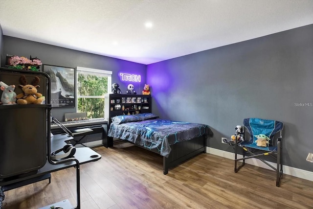 bedroom featuring a textured ceiling, wood finished floors, and baseboards