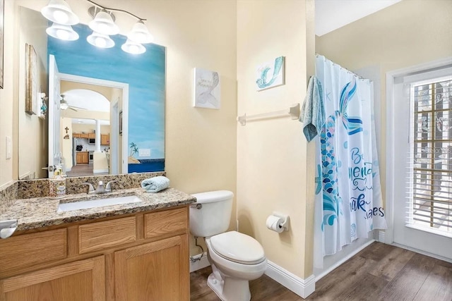 full bath with ceiling fan, toilet, wood finished floors, vanity, and baseboards