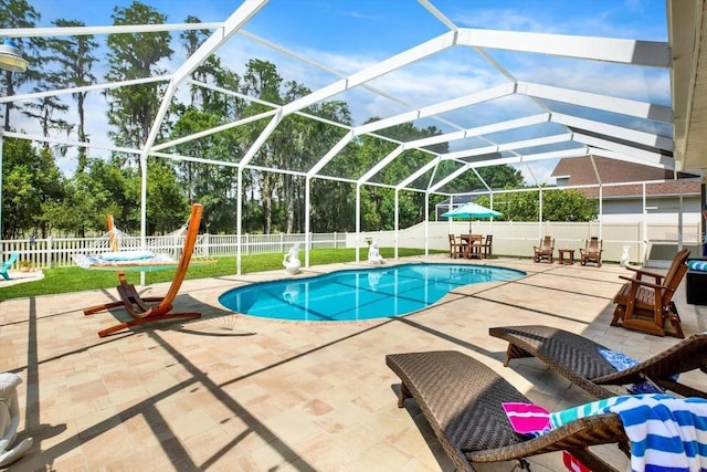 view of swimming pool featuring a patio, glass enclosure, a fenced backyard, and a fenced in pool