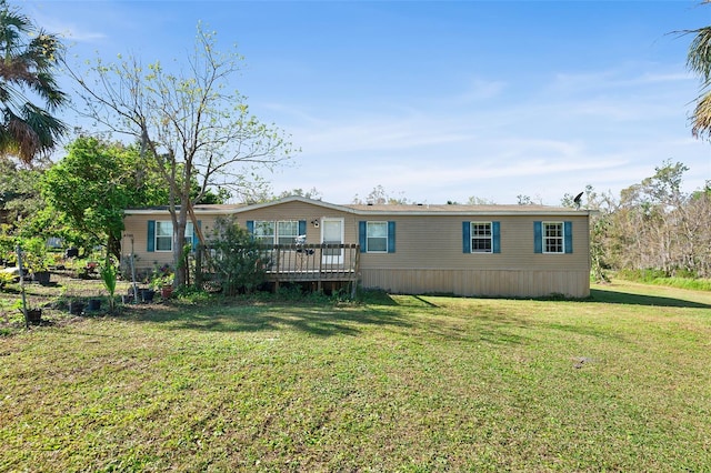 back of property with a deck and a lawn