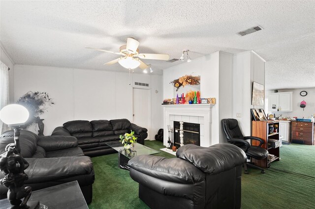 carpeted living room featuring a ceiling fan, a textured ceiling, visible vents, and a tiled fireplace