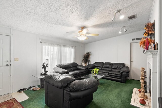 carpeted living room featuring ceiling fan, a textured ceiling, a fireplace with flush hearth, and visible vents