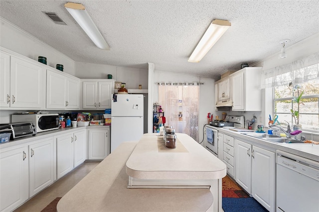 kitchen with under cabinet range hood, white appliances, a sink, visible vents, and light countertops