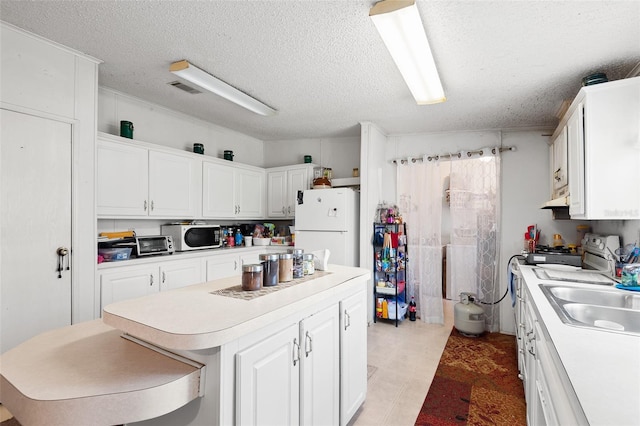 kitchen featuring light countertops, freestanding refrigerator, white cabinets, a kitchen island, and range