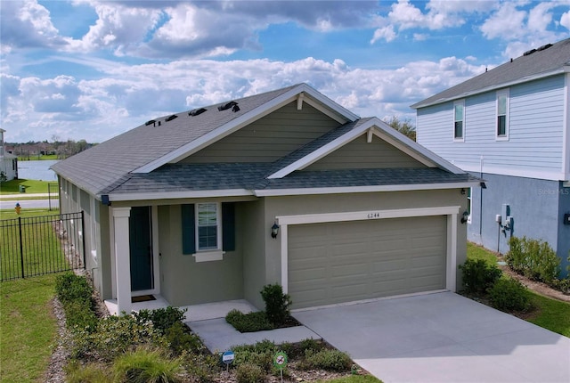 view of front facade with roof with shingles, stucco siding, concrete driveway, fence, and a garage