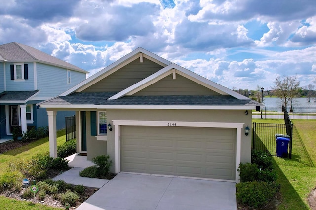 view of front facade featuring concrete driveway, a shingled roof, an attached garage, and fence