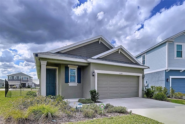 view of front facade featuring a garage, concrete driveway, fence, and stucco siding