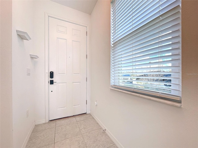 doorway with light tile patterned floors and baseboards