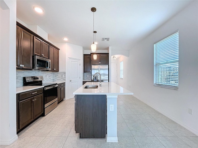 kitchen with arched walkways, tasteful backsplash, appliances with stainless steel finishes, a sink, and dark brown cabinetry