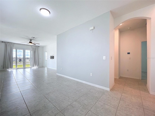 unfurnished room with arched walkways, visible vents, baseboards, and light tile patterned floors