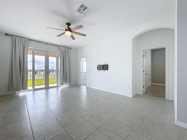 unfurnished room featuring arched walkways, french doors, visible vents, ceiling fan, and tile patterned floors