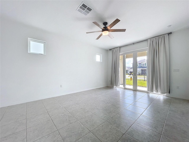 tiled spare room with baseboards, french doors, visible vents, and a ceiling fan