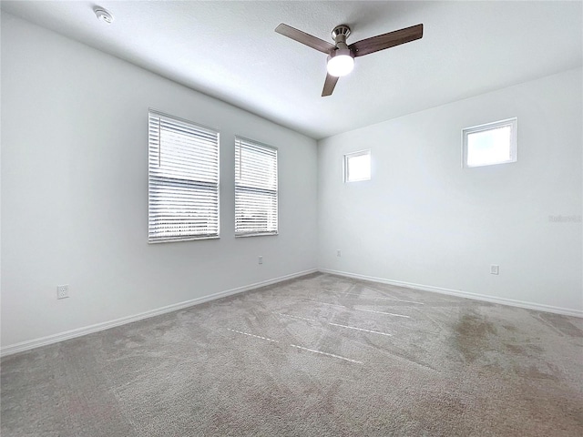 carpeted spare room featuring a ceiling fan and baseboards