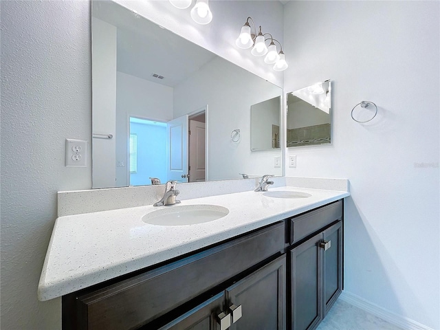 full bath featuring double vanity, baseboards, visible vents, and a sink