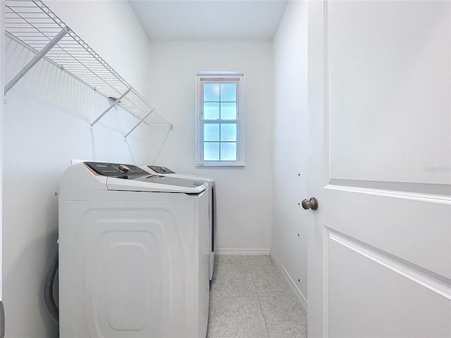 clothes washing area with baseboards, laundry area, light tile patterned floors, and washer and dryer