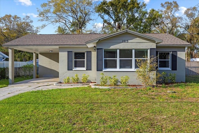 view of front of property featuring an attached carport, concrete block siding, fence, and a front lawn