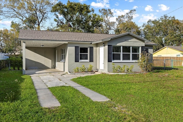 view of front of home with an attached carport, concrete block siding, a front yard, fence, and concrete driveway