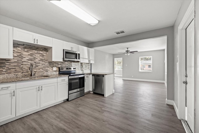 kitchen featuring visible vents, a sink, tasteful backsplash, white cabinetry, and appliances with stainless steel finishes