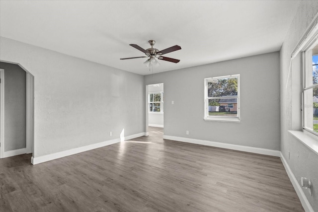 unfurnished room with baseboards, wood finished floors, and a ceiling fan