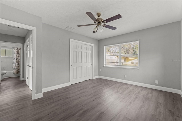 unfurnished bedroom with a closet, baseboards, a textured ceiling, and dark wood finished floors