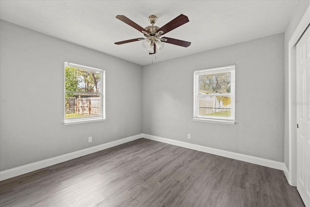 unfurnished bedroom with a closet, multiple windows, baseboards, and wood finished floors