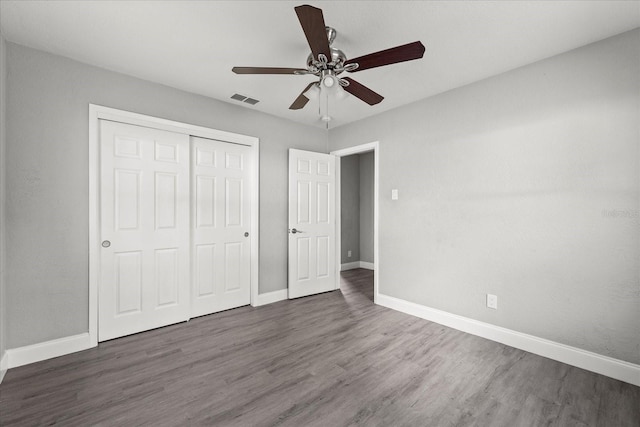 unfurnished bedroom with wood finished floors, visible vents, a closet, and baseboards