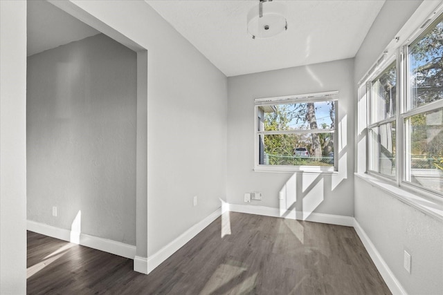 empty room featuring dark wood-type flooring and baseboards