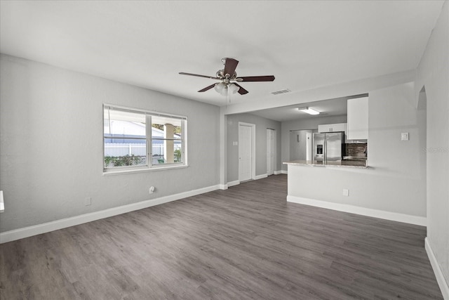 unfurnished living room with visible vents, ceiling fan, baseboards, and dark wood-style flooring