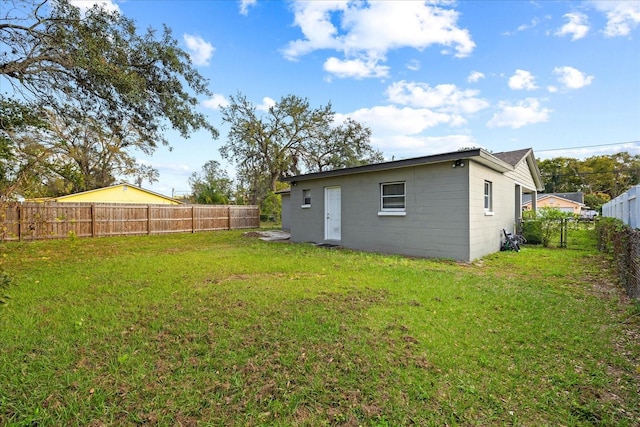 rear view of house featuring a lawn and a fenced backyard