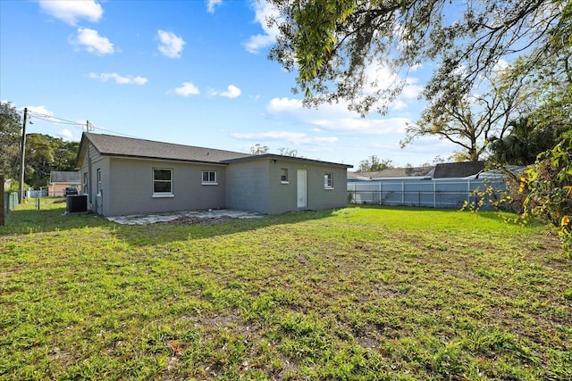 rear view of property featuring a patio area, a lawn, central AC, and a fenced backyard