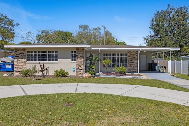 ranch-style home with an attached carport, a front yard, fence, driveway, and stucco siding