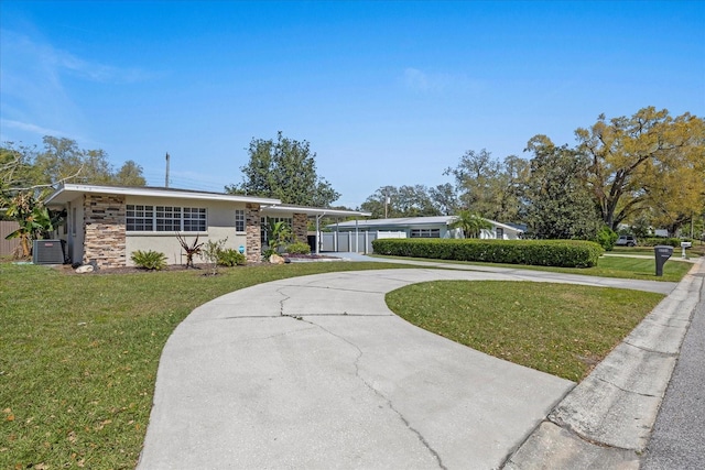 view of front of home with central air condition unit, curved driveway, a front yard, and stone siding