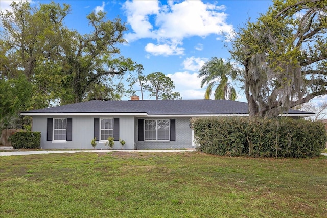 ranch-style house with brick siding, a chimney, and a front yard