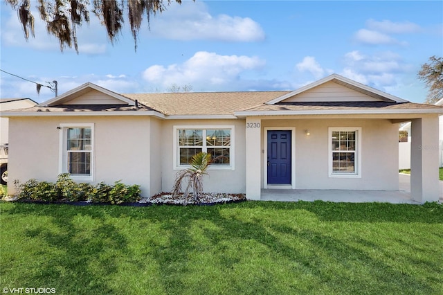 ranch-style house featuring roof with shingles, a front yard, and stucco siding