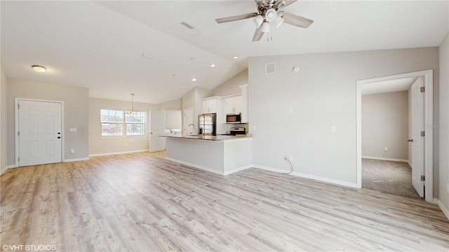 unfurnished living room featuring light wood-style flooring, visible vents, vaulted ceiling, and a sink