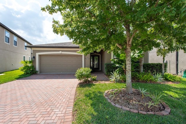 view of front facade with a front lawn, decorative driveway, an attached garage, and stucco siding