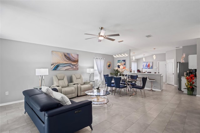 living area featuring a ceiling fan, visible vents, vaulted ceiling, and baseboards