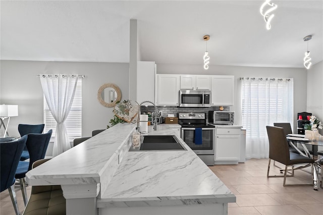 kitchen with a toaster, stainless steel appliances, tasteful backsplash, white cabinets, and a sink