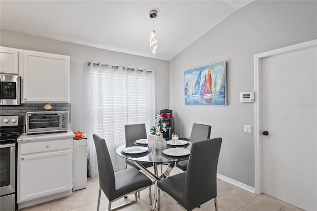 dining space with lofted ceiling, light tile patterned flooring, baseboards, and a toaster