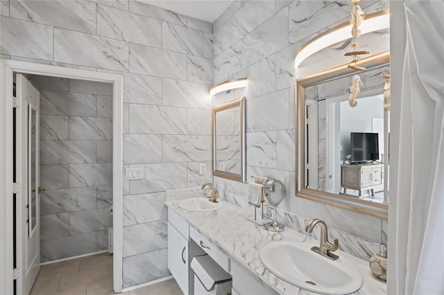 bathroom with double vanity, tile walls, a sink, and tile patterned floors